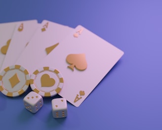 A set of playing cards displaying four aces is laid out on a surface. Alongside them, there are two poker chips with heart and diamond symbols, and three six-sided dice showing different numbers. The background is a smooth gradient of purple, creating a thematic gaming or casino atmosphere.